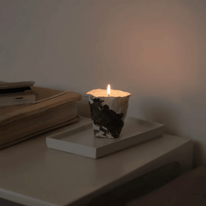 Candle in a decorative holder on a shelf with books in a dimly lit room