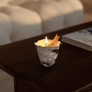 Small candle in a paper cup with a note on a wooden surface.